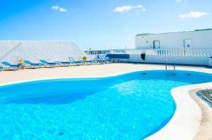 a swimming pool with chairs and a building at Casa Tigot in Puerto del Carmen