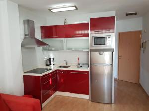 kuchnia z czerwonymi szafkami i lodówką ze stali nierdzewnej w obiekcie Mini Penthouse close to beach with nice seaviews w mieście Nerja
