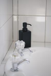 a bathroom sink with a soap dispenser and aaucet at Hugo & Carters Backpackers & Motel in Tauranga