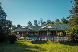 a resort with a pool and tables and umbrellas at Hostal Canela in Termas del Daymán
