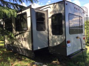 a trailer parked in the grass with its door open at Sequoia Forest Retreat in Badger