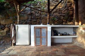 a kitchen with a refrigerator next to a stone wall at Casa Taller in Barichara