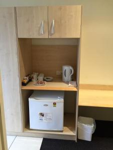 a cabinet with a refrigerator in a room at Red Bridge Motor Inn in Woombye