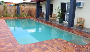 a swimming pool with blue water in a yard at Spanish Lace Motor Inn in Townsville