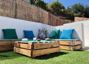 a patio with two benches and pillows on the grass at Casa da Pedra - Aljezur, always the sun in Aljezur