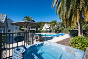 a swimming pool with an umbrella next to a house at Tinkerbell Cottage 2-4 Bedroom- Russell Cottages Collection in Russell