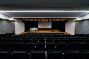 an empty auditorium with black chairs and a stage at HI Braga - Pousada de Juventude in Braga