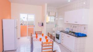 - une cuisine avec une table et des tasses en orange dans l'établissement Apartamento Praia Grande Ubatuba 2 vagas garagem Internet WiFi, à Ubatuba