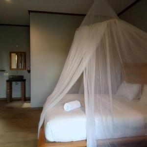 a bedroom with a bed with a mosquito net at Emir Surfcamp in Pulukan