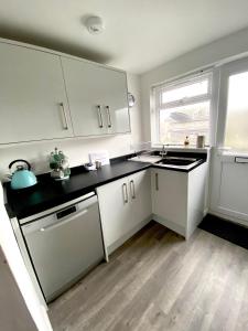 a kitchen with white cabinets and a black counter top at Surf's Up in Perranporth, Cornwall Coastal Holidays in Perranporth