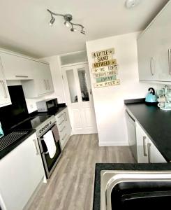a kitchen with white cabinets and a black counter top at Surf's Up in Perranporth, Cornwall Coastal Holidays in Perranporth