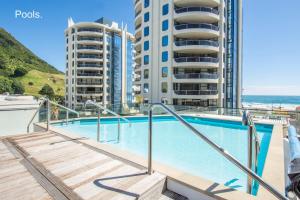 a swimming pool with two tall buildings in the background at Ocean Eleven 22 in Mount Maunganui