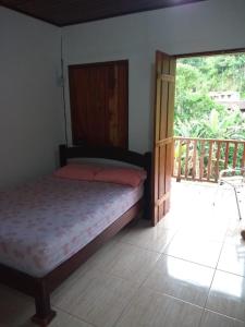 ein Schlafzimmer mit einem Bett und einem großen Fenster in der Unterkunft Cantinho do Aconchego in Paraty