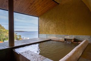 a pool of water in a room with a view of the ocean at Isaribi (No Children) in Higashiizu
