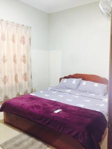 Un dormitorio con una cama con sábanas moradas y una ventana en Sweet Home, en Phnom Penh