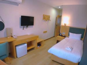 a room with a bed and a desk with a television at Fujinomori Hotel in Fujikawaguchiko