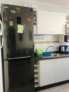 una nevera negra en una cocina con armarios blancos en Cosmopolita Verde, en La Serena