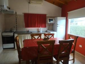 cocina con mesa y cortina roja en Cabañas Cuncumen en Los Reartes