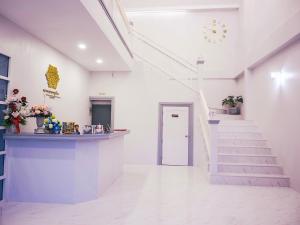 a white hallway with stairs and a clock on the wall at Promporn Boutique Hotel in Nan