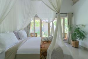 1 dormitorio con 1 cama blanca con dosel en Angels Bungalow Nusa Penida, en Nusa Penida