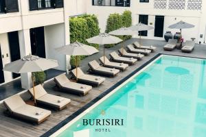 Buri Siri Boutique Hotel في شيانغ ماي: فندق فيه مسبح وكراسي صالة ومظلات