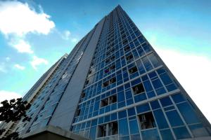 a tall glass building with a blue sky in the background at Minimalist and Homey Studio Menteng Park Apartment By Travelio in Jakarta