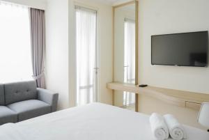 a hotel room with a bed and a tv and a chair at Minimalist and Homey Studio Menteng Park Apartment By Travelio in Jakarta