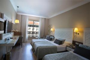 a hotel room with two beds and a desk at Fame Residence Kemer & Spa in Kemer