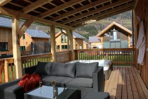 a patio with a couch and a hot tub on a deck at Aron Chalet Kreischberg 10A in Sankt Lorenzen ob Murau