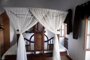 1 dormitorio con cama con dosel y cortinas blancas en Hiliki House en Zanzíbar
