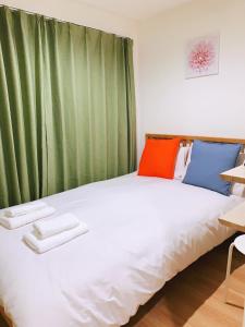 a large white bed in a room with green curtains at 秋の旅館 秋叶原 Tokyo Akihabara in Tokyo