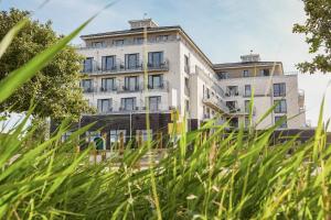 a tall white building with grass in front of it at Ferienwohnungen Küstenperle in Büsum
