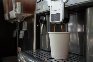 a coffee machine with a cup on a counter at Botanic Service Room at Impact Muangthongthani - SHA Certified in Nonthaburi