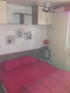 Schlafzimmer mit einem roten Bett und einem Deckenventilator in der Unterkunft Mobilhome sur camping le kontiki **** ramatuelle in Saint-Tropez