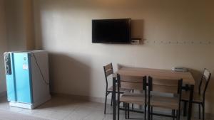 um quarto com uma mesa, um frigorífico e uma televisão em Mana Residence em Hat Yai