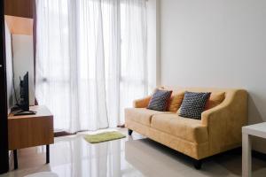 a living room with a couch in front of a window at Convenient and Luxurious 2BR Asatti Apartment By Travelio in Pagedangan