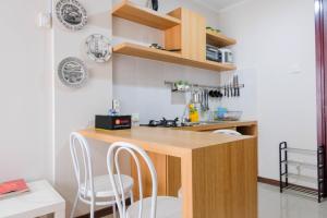 a kitchen with a counter and chairs in a room at Convenient and Luxurious 2BR Asatti Apartment By Travelio in Pagedangan