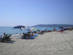 a group of people sitting on a beach with umbrellas at Mobilhome sur camping le kontiki **** ramatuelle in Saint-Tropez