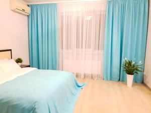 a bedroom with blue curtains and a bed and a window at Шикарные апартаменты 3 минуты пешком от м Позняки in Kyiv