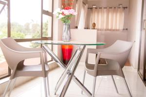 a glass table with two chairs and a vase with flowers at Villa Prince in Harare