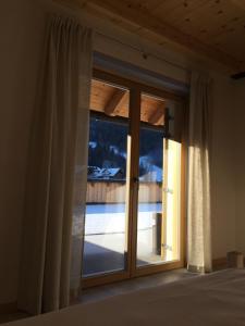 a bedroom with a sliding glass door to a balcony at Da Alsido in Camporosso in Valcanale