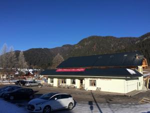 a white building with cars parked in a parking lot at Da Alsido in Camporosso in Valcanale