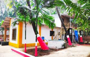 ein Haus mit zwei Palmen davor in der Unterkunft Ashish Baug Cottage in Alibag