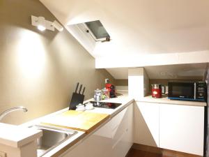 uma pequena cozinha com armários brancos e um micro-ondas em Vico - Corso Como 11 em Milão
