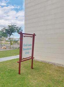 a sign sitting in the grass in front of a building at Sifah Resort Studio in As Sīfah