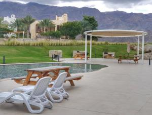 a patio with a picnic table and chairs next to a pool at Sifah Resort Studio in As Sīfah