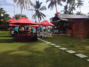 a group of people sitting at tables under red umbrellas at Seacoast Sanctuary Beach Hotel in Hiriketiya