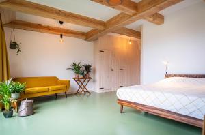 ein Schlafzimmer mit einem Bett und einer gelben Couch in der Unterkunft Wijngaard de Kroon van Texel in Den Burg + 16 Fotos