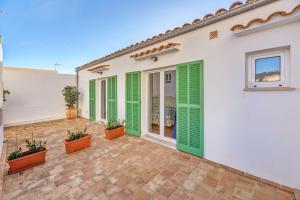 a house with green shutters and a patio at Villa Magdalena in Cala Ratjada