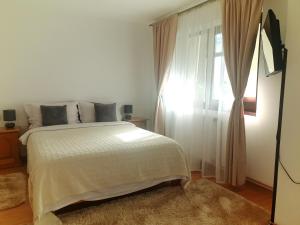 a bedroom with a white bed and a window at Pension Casa Aurora in Vama